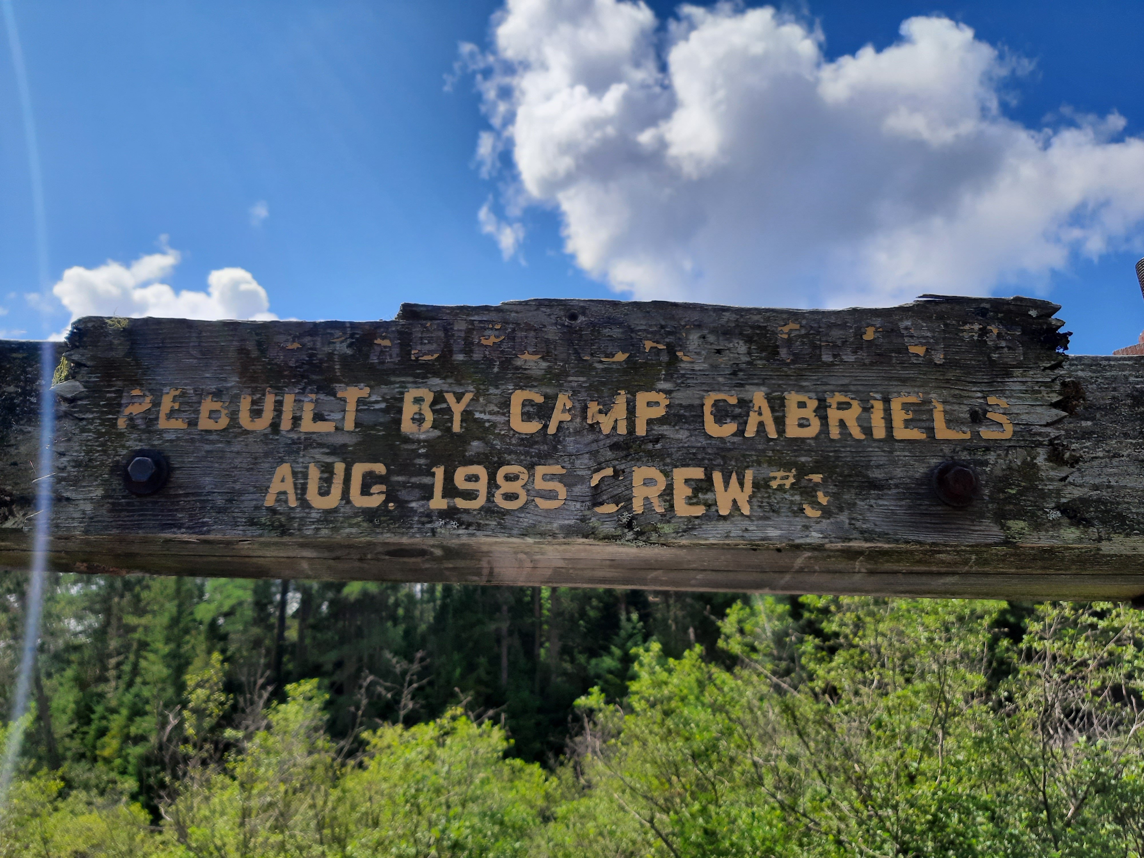 wooden sign from 1985 showing that Camp Gabriels inmates had rebuilt a large wooden bridge on a popular hiking trail in Ray Brook